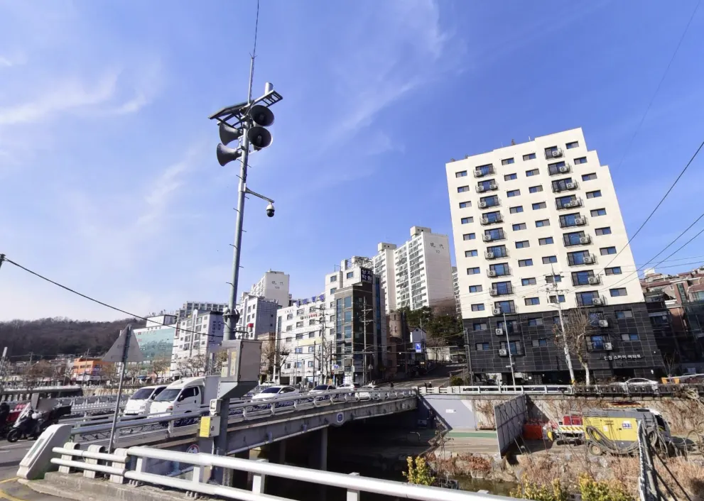 Observation device on a pole near a bridge and residential buildings
